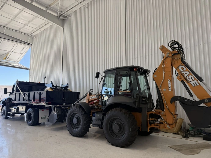 Backhoe loader and flatbed truck parked inside a hangar | American Jet Center